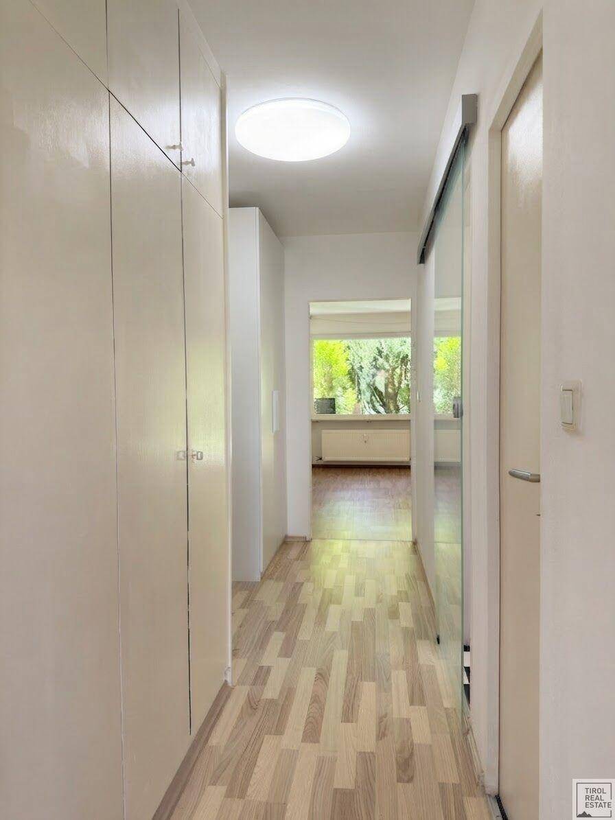 Langer Flur mit Einbauschränken und Blick in einen hellen Wohnbereich.
