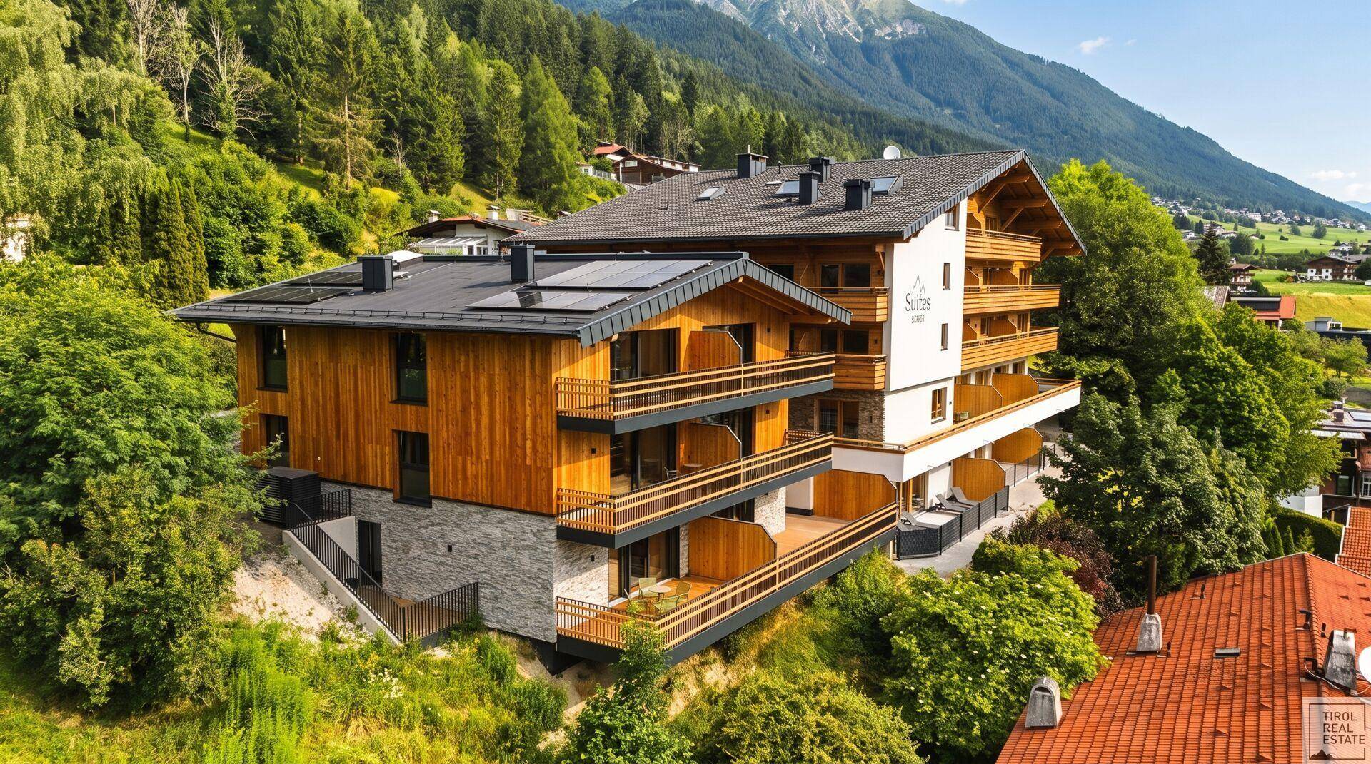 Attraktives Neubaugebäude mit Holzfassade und Balkonen, eingebettet in die grüne Berglandschaft.