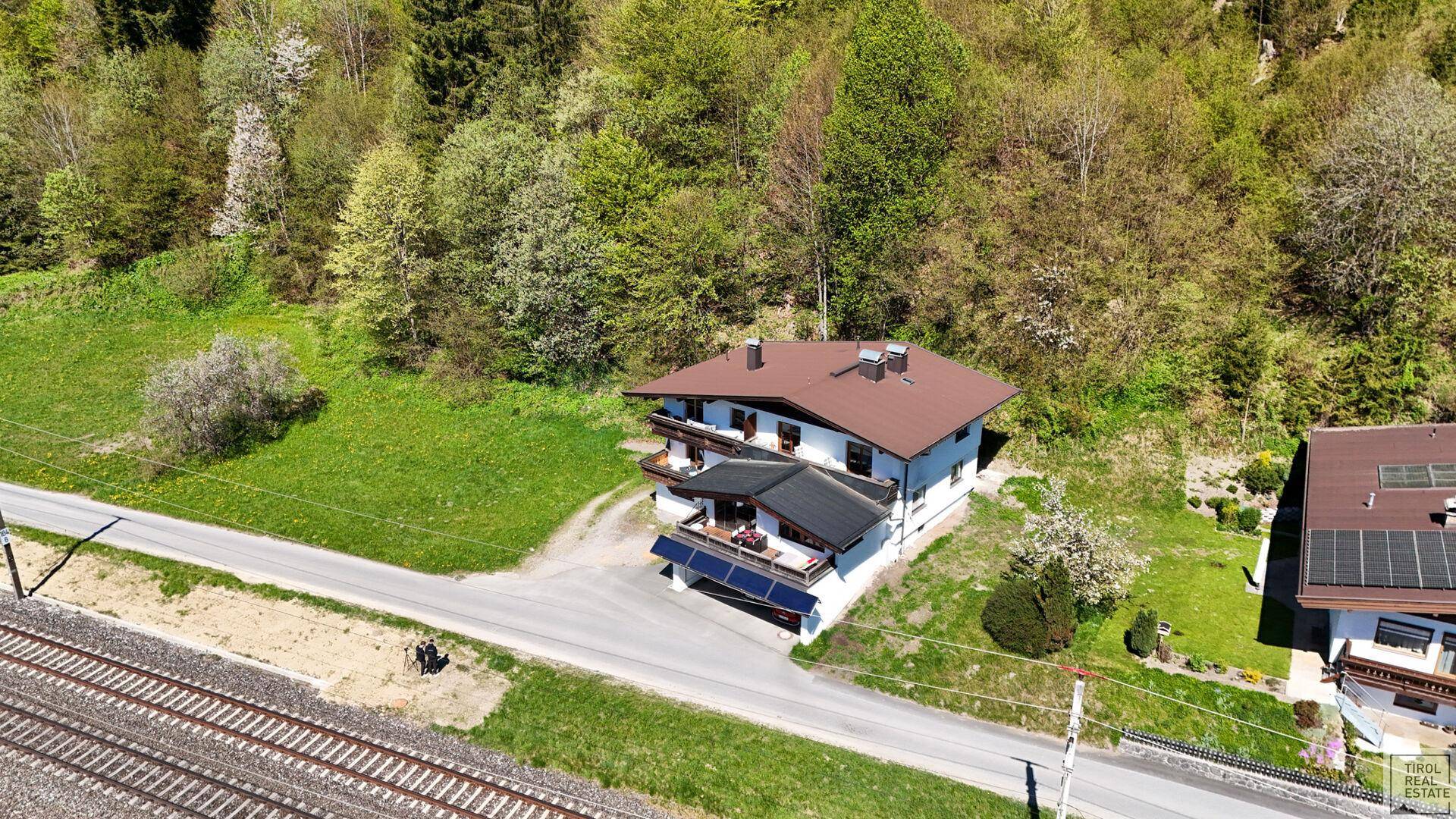 Luftaufnahme eines Hauses in ländlicher Umgebung mit viel Grün und Bergblick.