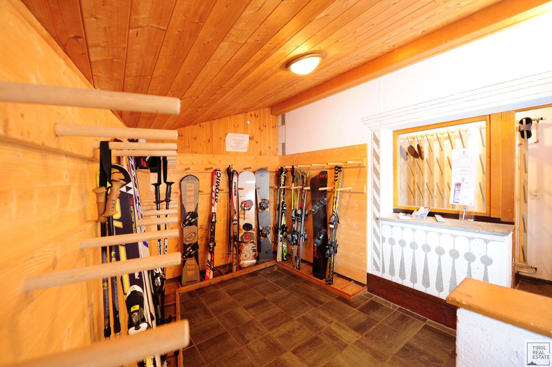 Skiraum mit Holzverkleidung, Fliesenboden und reichlich Platz für Wintersportausrüstung.