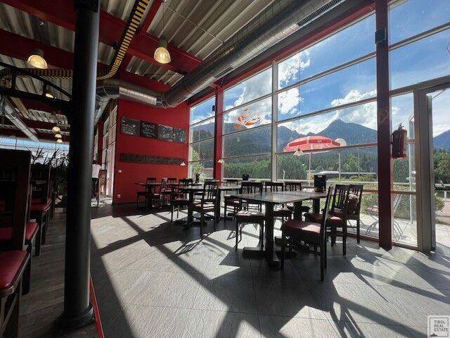 Geräumiger Essbereich mit hohen Decken, großen Fenstern und Panoramablick auf die umliegenden Berge.