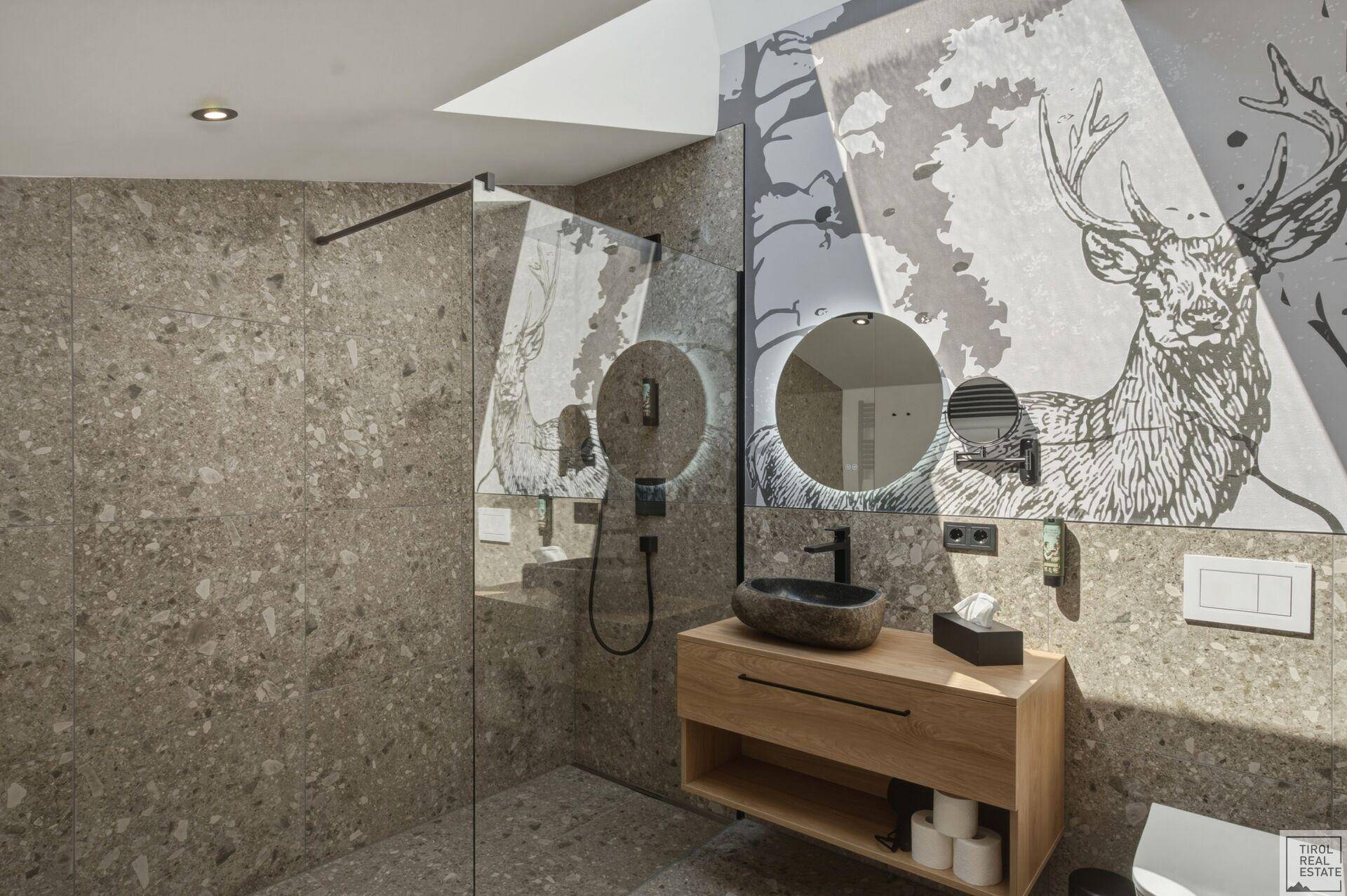 Modernes Badezimmer mit Steinfliesen, begehbarer Dusche und einzigartigem Waschbecken.