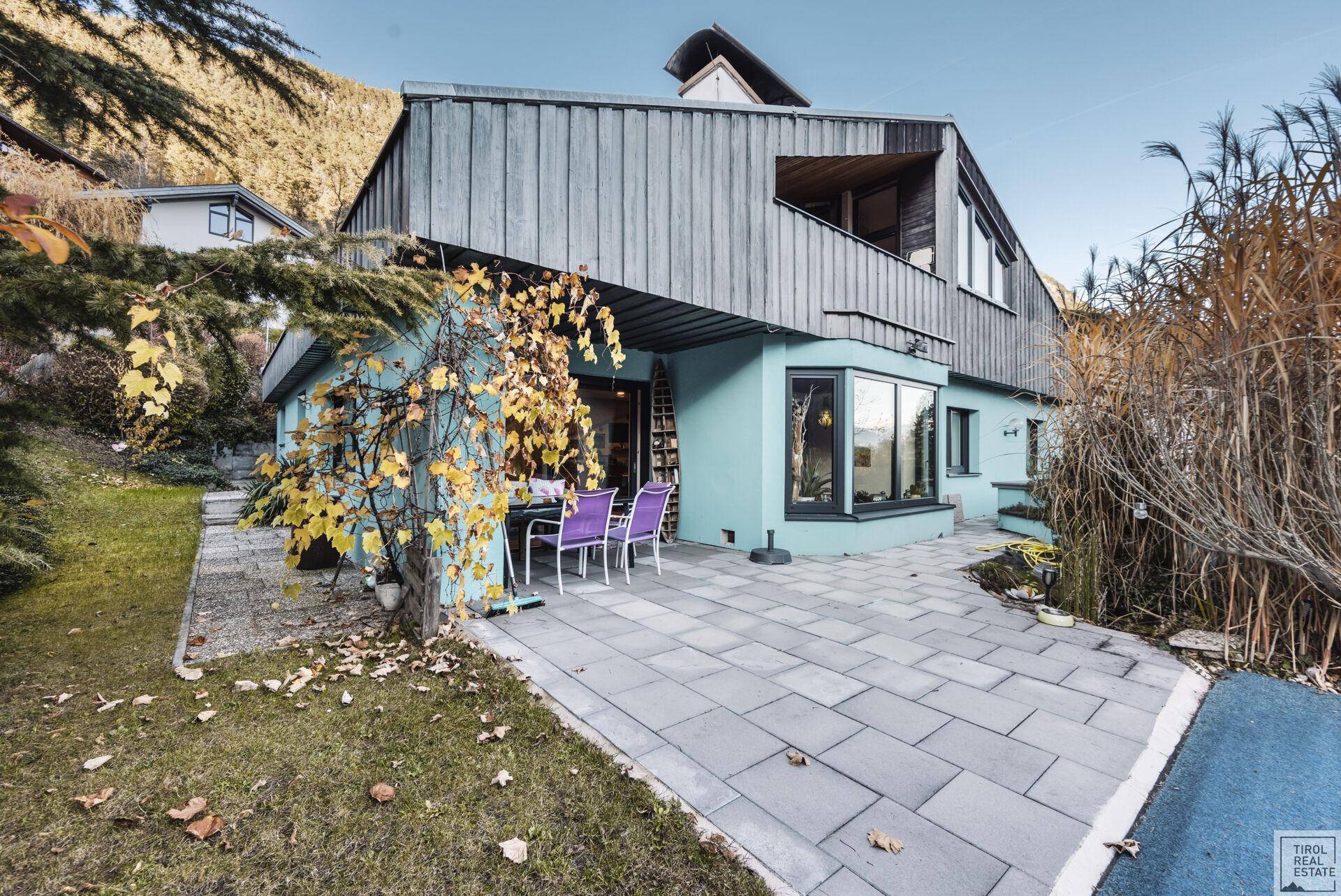 Außenansicht des Hauses mit großer gepflasterter Terrasse und Sitzgelegenheiten.