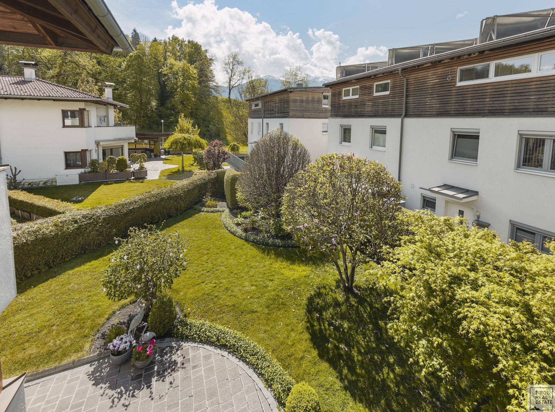 Überblick über den gepflegten Gartenbereich und die umliegenden Häuser mit Bergblick.