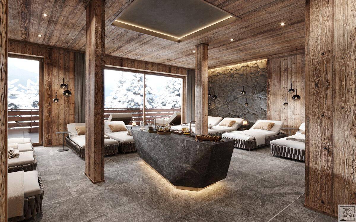 Geräumiger Wellnessbereich mit bequemen Liegen, Steintresen und Panoramablick auf die verschneite Landschaft.