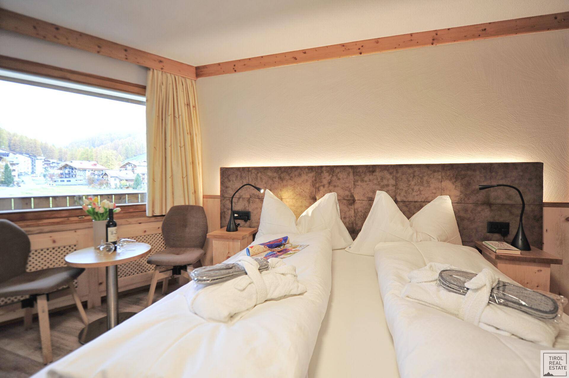 Nahaufnahme des Doppelbettes und eines kleinen Tisches mit Stühlen im Schlafzimmer, mit Blick nach draußen.