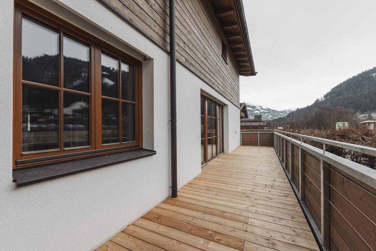 Langer Balkon mit Holzboden und Blick auf die umliegende Berglandschaft.