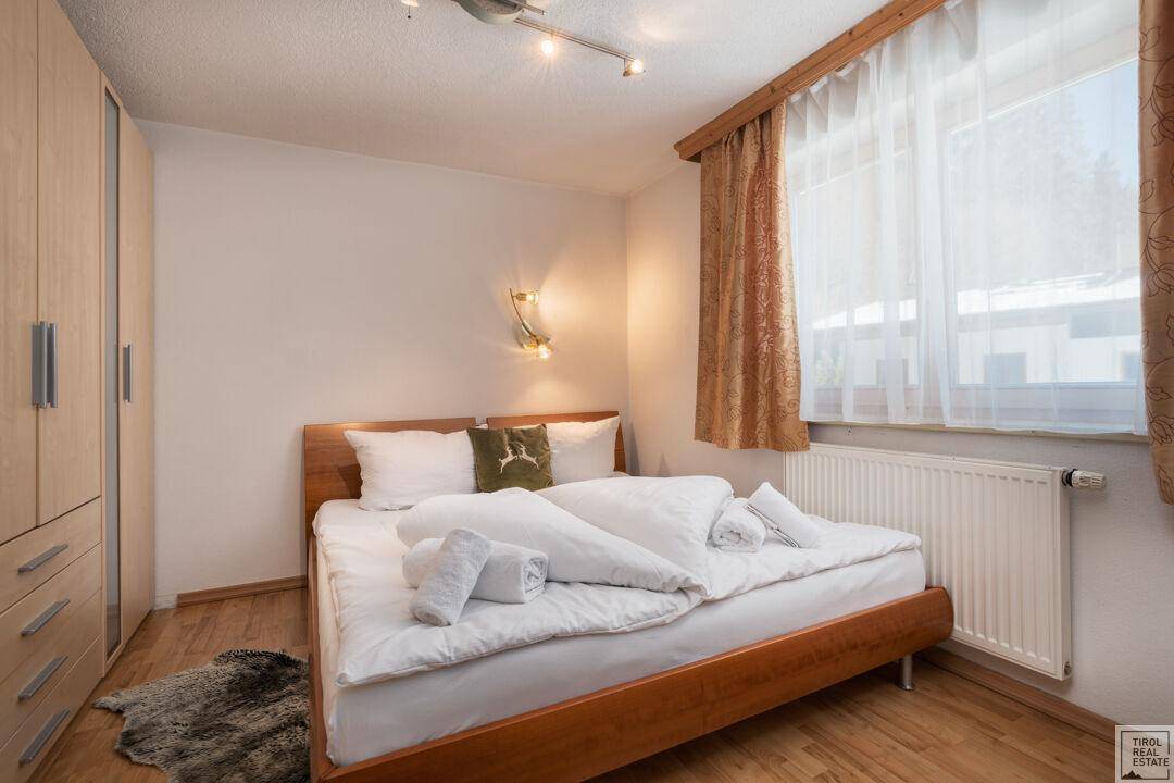 Helles Schlafzimmer mit Holzboden, großem Bett und praktischem Kleiderschrank für Stauraum.