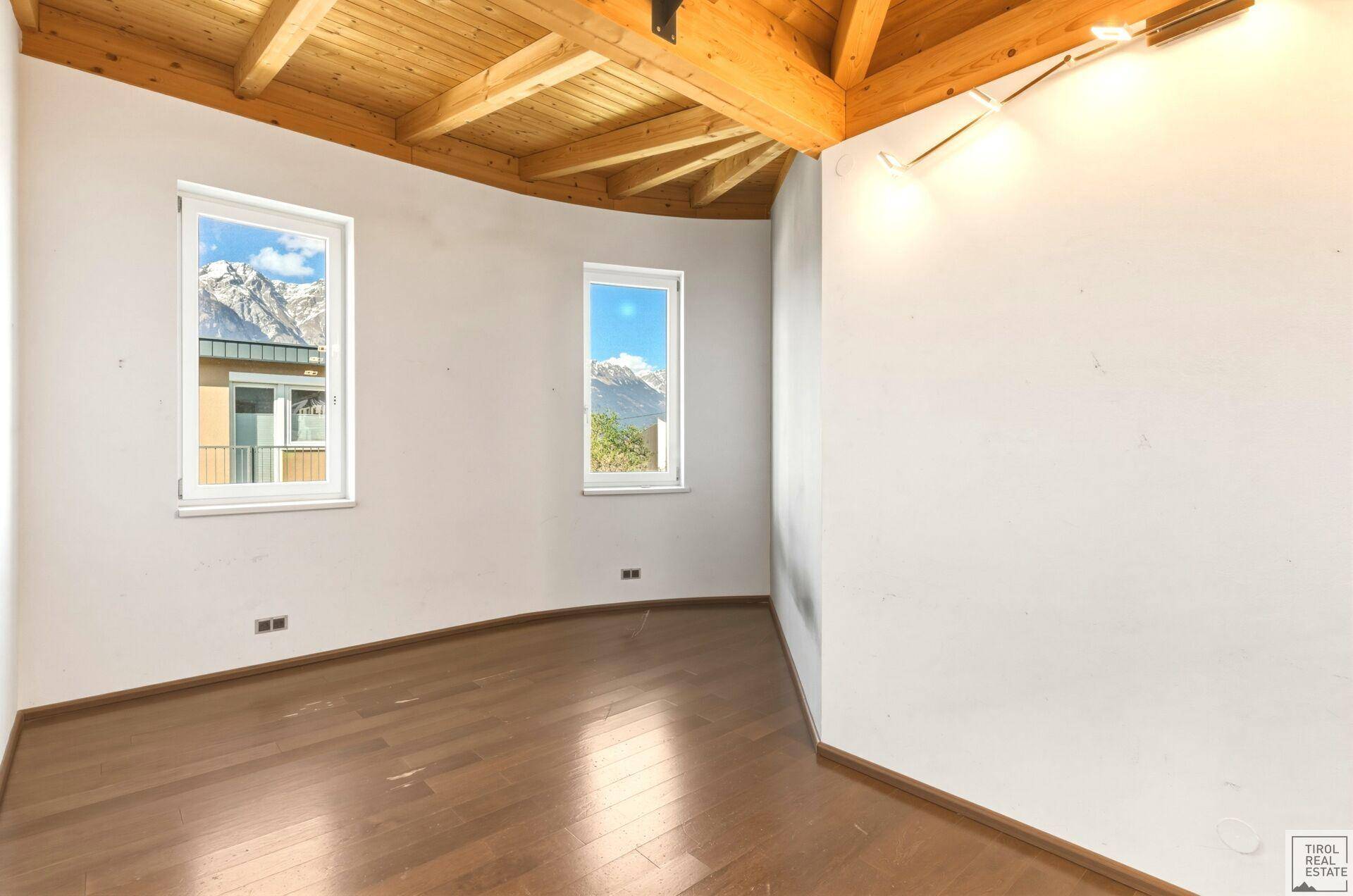 Rundes Schlafzimmer mit Holzboden und Holzbalkendecke, bietet einen einzigartigen Bergblick.
