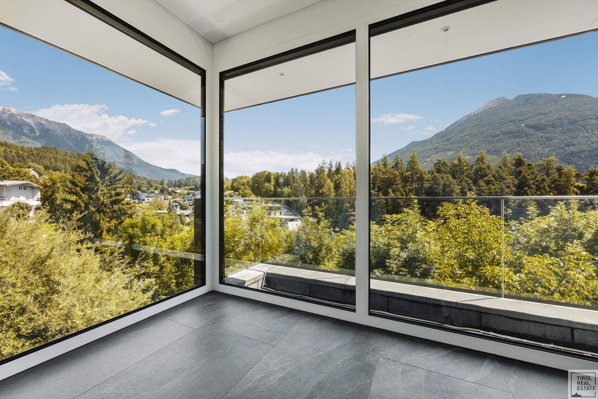 Eckzimmer mit raumhohen Fenstern bietet einen weiten Blick auf die umliegende Natur und Berge.