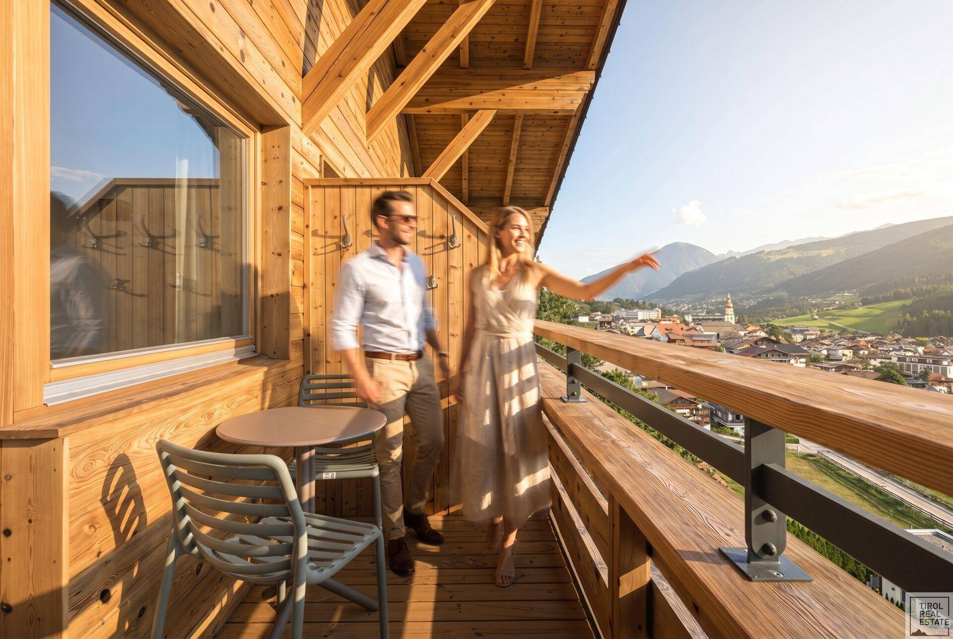 Holzverkleideter Balkon mit Sitzgelegenheiten und weitem Blick über das Tal und die Stadt.