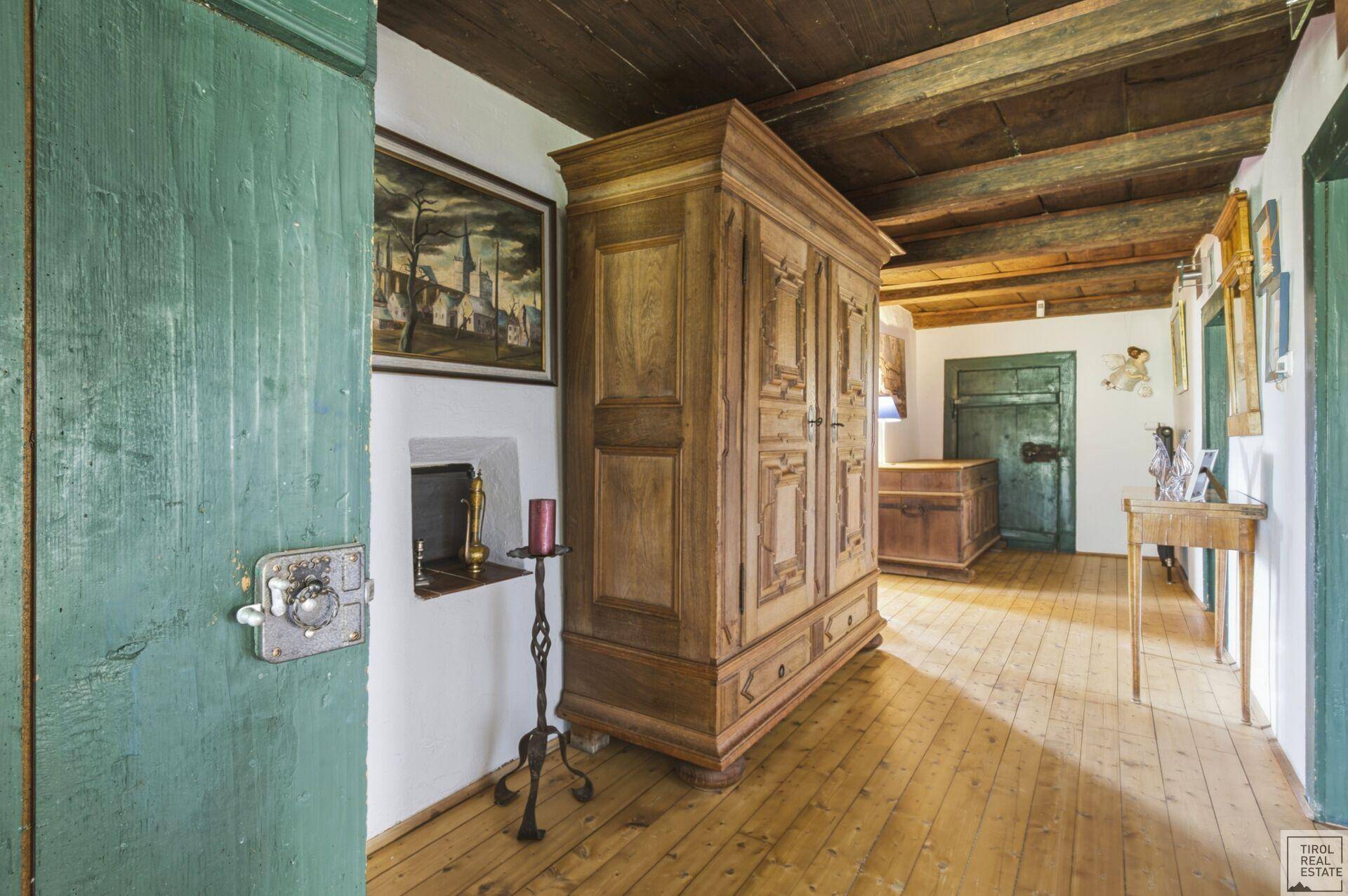 Traditioneller Flur mit Holzdielenboden, Holzbalkendecke und antiken Möbeln.