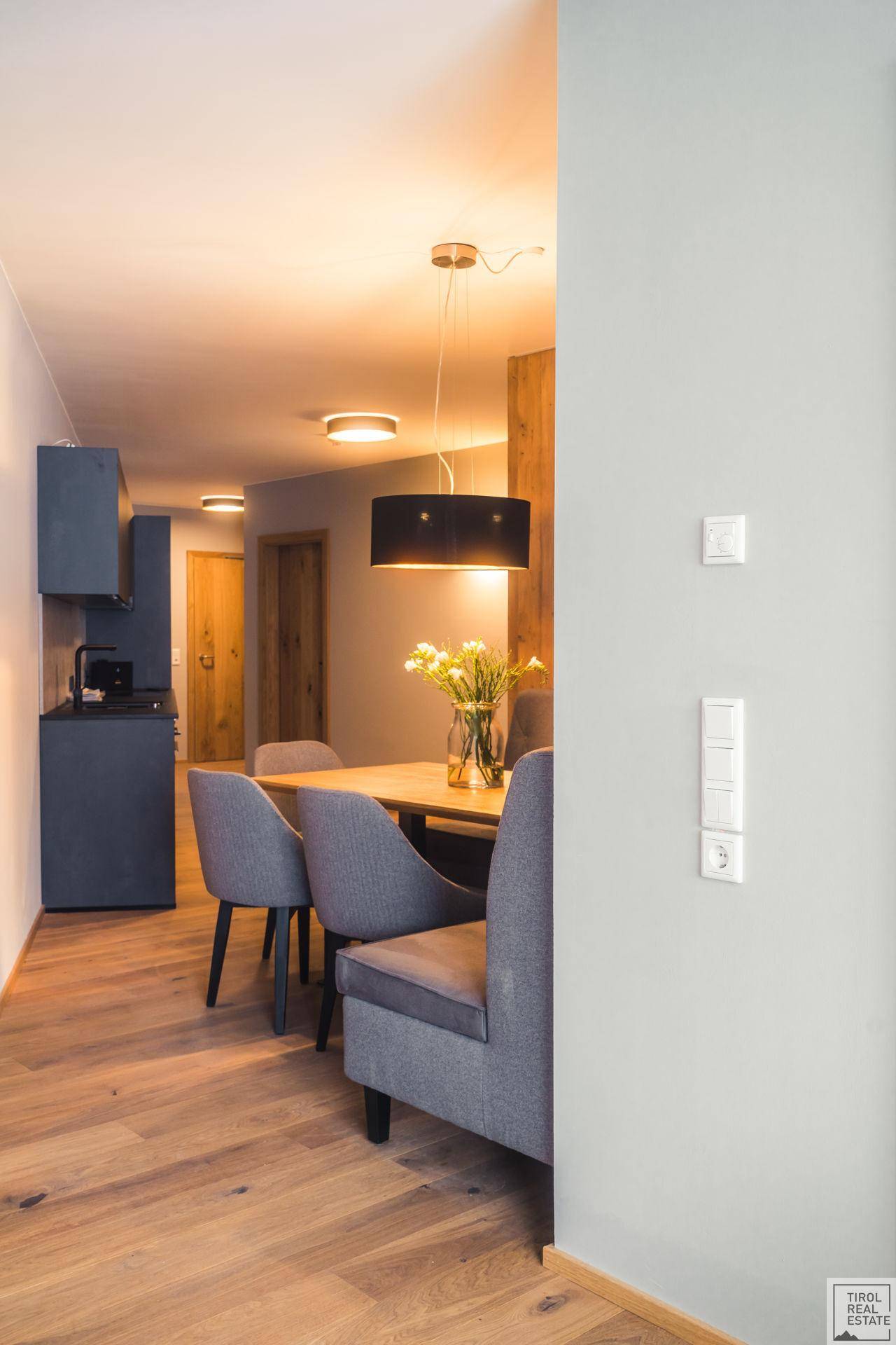Moderner Essbereich mit Holzboden, stilvollen Stühlen und Blick in die Küche.