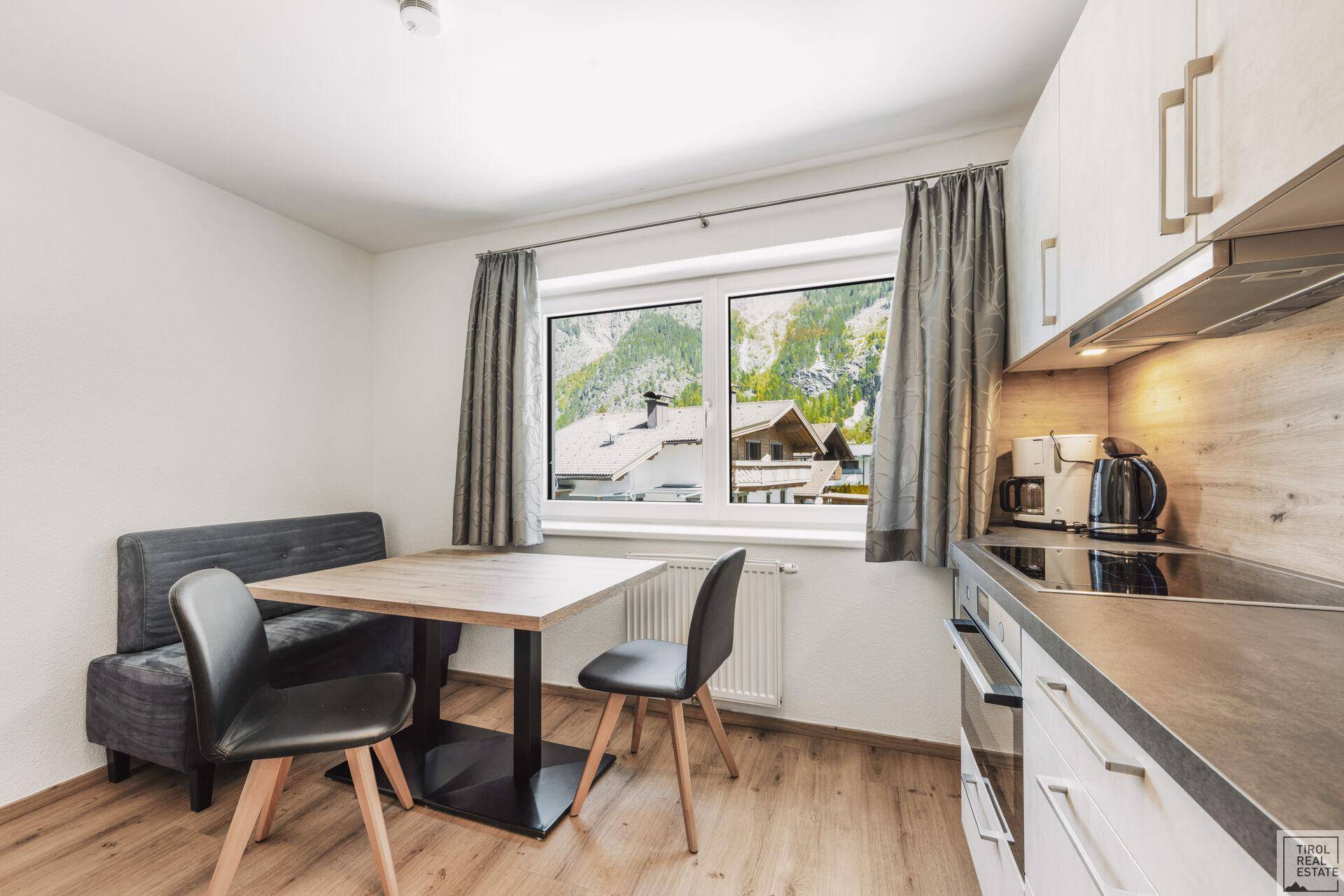Moderne Einbauküche mit Essbereich, Holzboden und Fenster mit Bergblick.