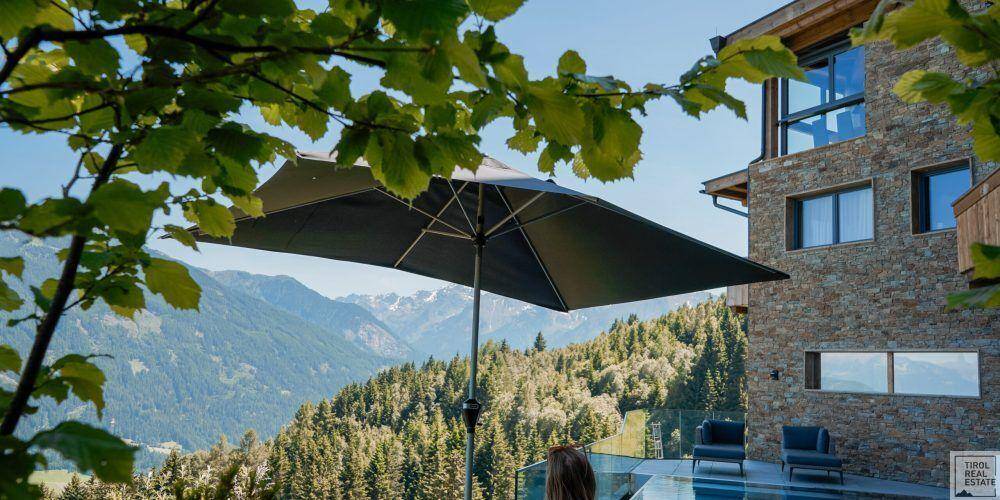 Außenbereich mit Pool, Sonnenschirm und spektakulärem Blick auf die Bergwelt.