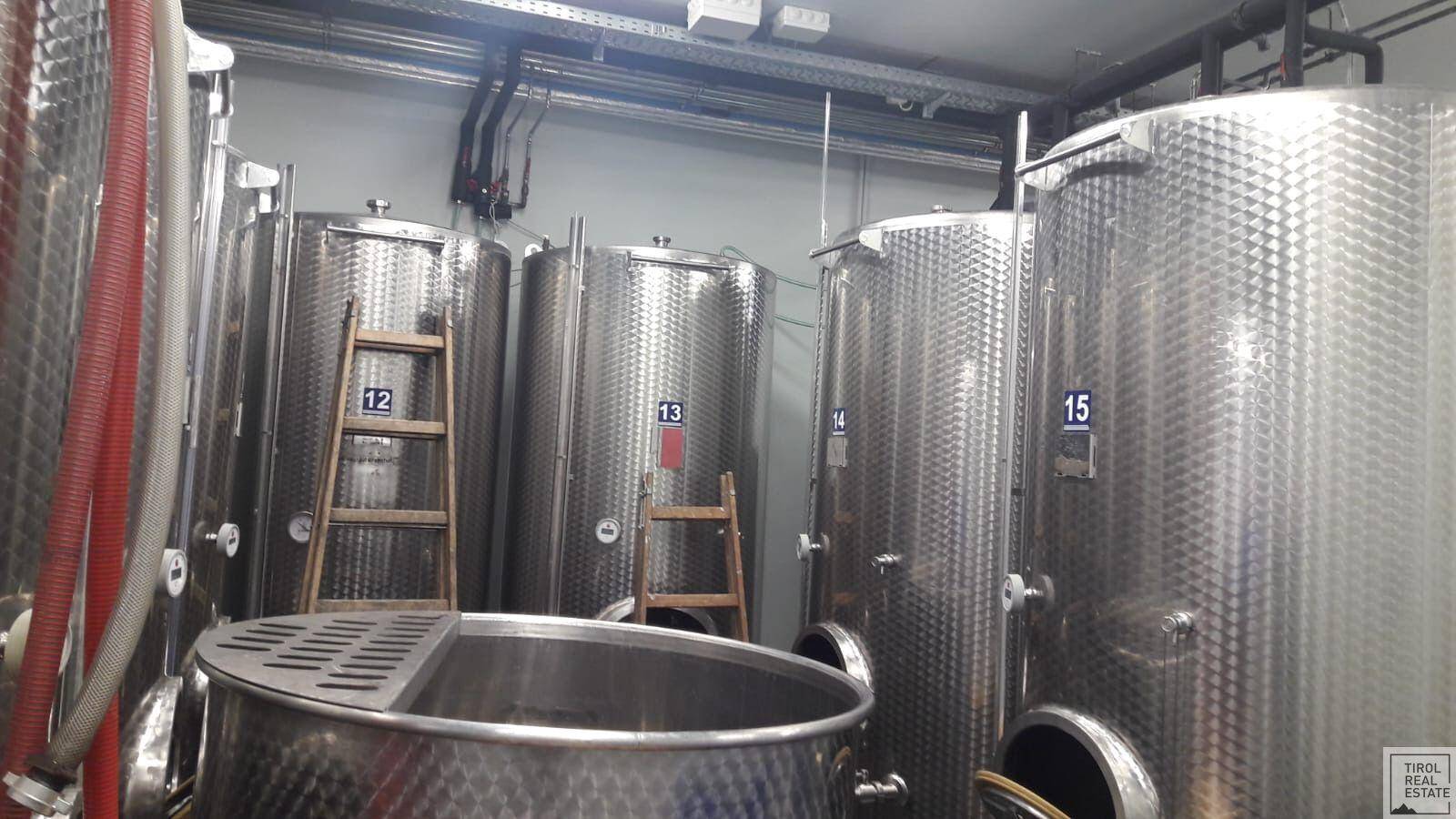 Industrieller Raum mit großen Edelstahltanks und Leitungen, wahrscheinlich ein Weinkeller oder eine Produktionsstätte.