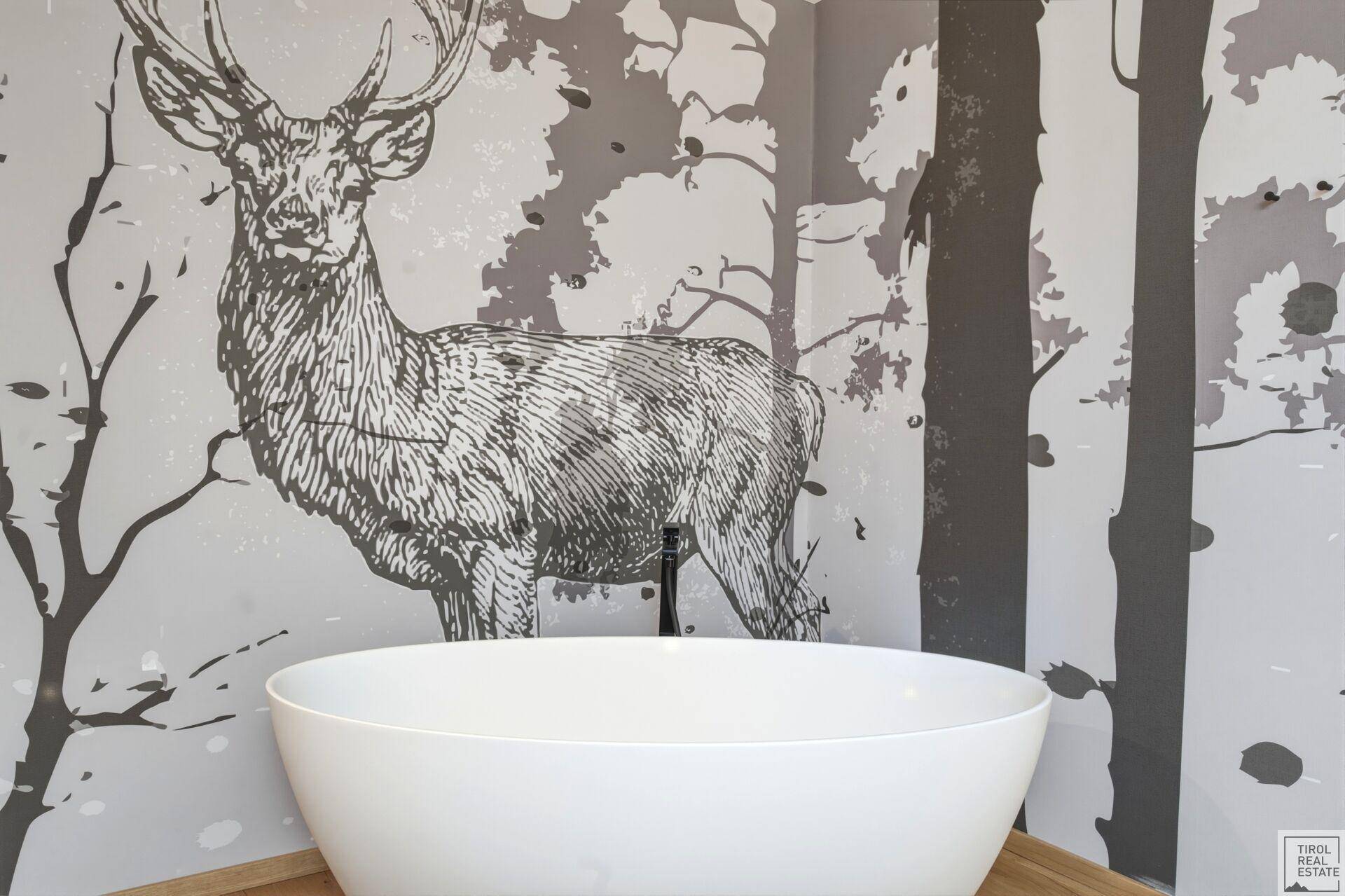 Freistehende Badewanne im Schlafzimmer mit dekorativer Wandgestaltung im alpinen Stil.