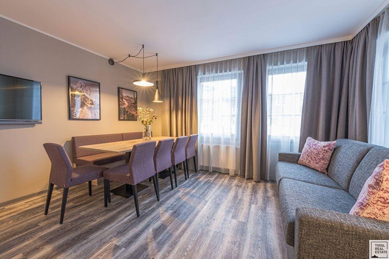 Geräumiger Wohn-Essbereich mit bequemer Couch, Esstisch und großen Fenstern für viel Licht.