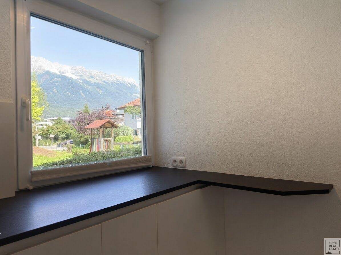 Küchenbereich mit Fenster, das einen weiten Blick auf die Berge und einen Spielplatz bietet.