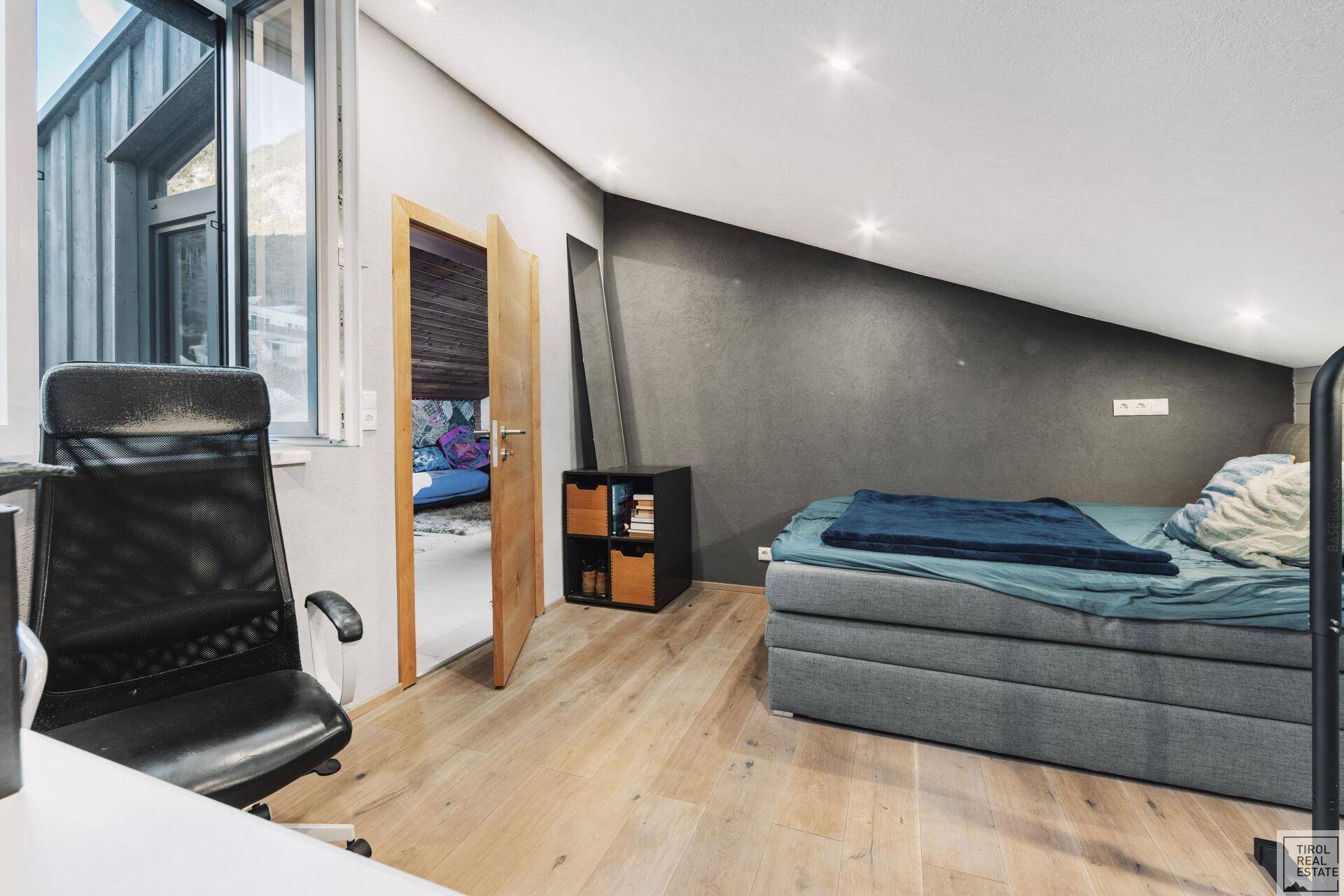 Schlafzimmer mit Holzboden, Schreibtisch und Blick auf die Berge.
