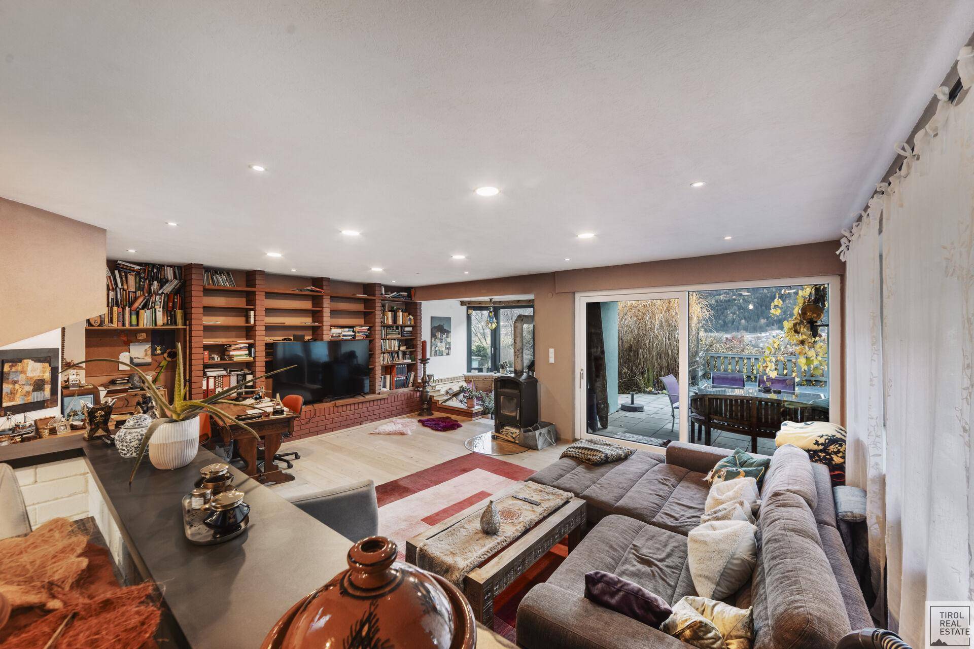 Gemütliches Wohnzimmer mit großem Sofa, Kaminofen und Zugang zur Terrasse.