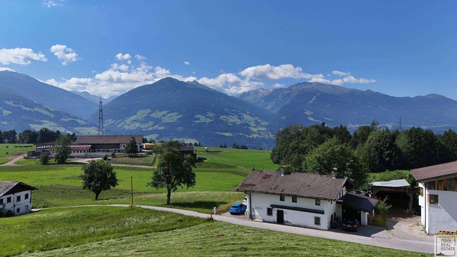 Weitläufige Landschaftsaufnahme mit dem Anwesen und umliegenden Bergen.