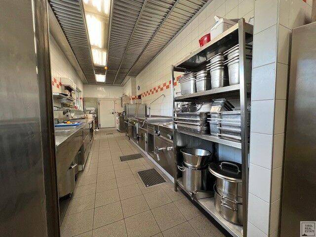Professionelle Großküche mit Edelstahlausstattung, Fliesenboden und effizienter Arbeitsumgebung.