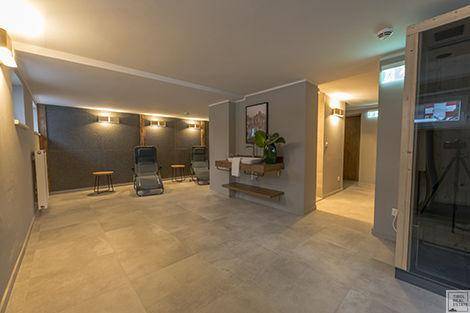 Geräumiger Wellnessbereich mit Liegen, einem Waschbecken und einer sichtbaren Sauna.