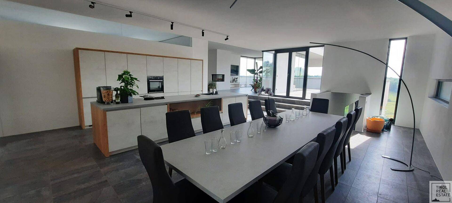 Geräumiger Essbereich mit langem Tisch und Stühlen, angrenzend an eine moderne Küche.