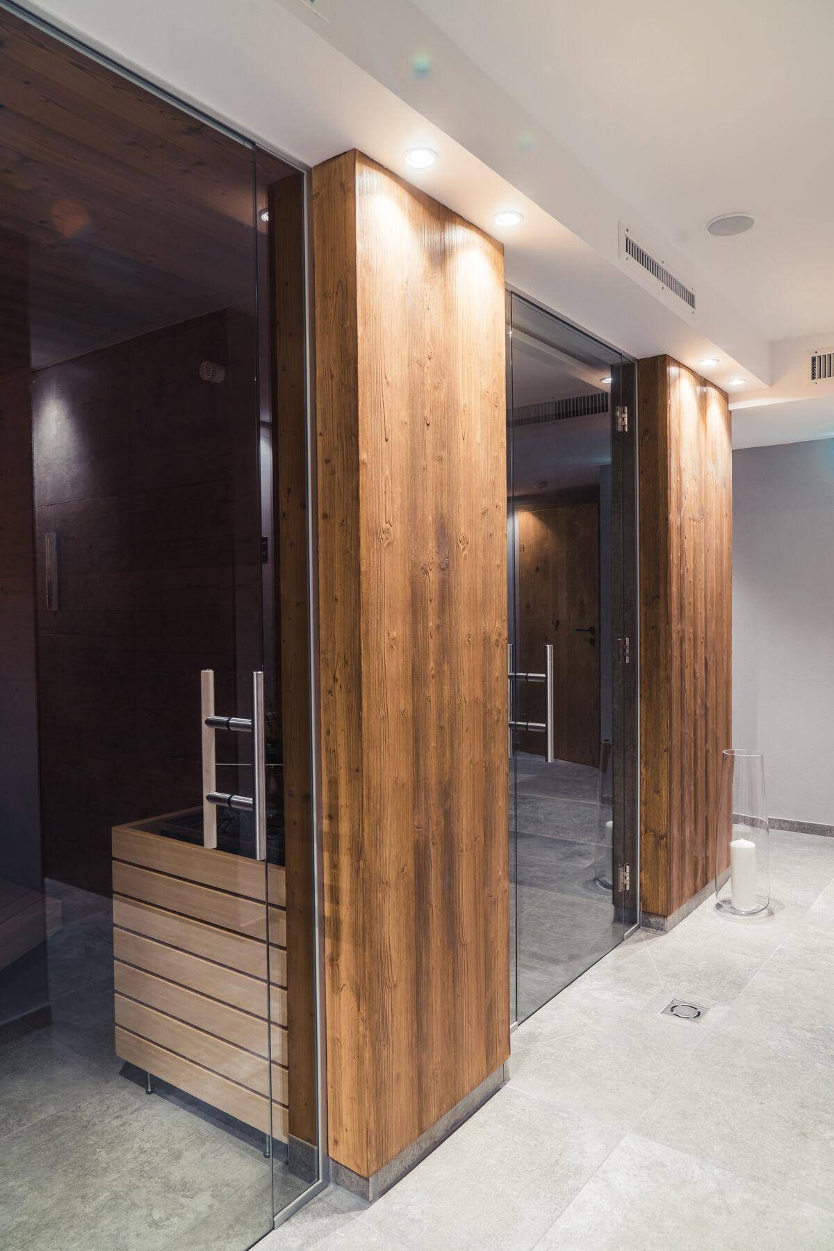 Detailansicht des Wellnessbereichs mit Holzelementen, Glaswänden und integrierter Sauna.