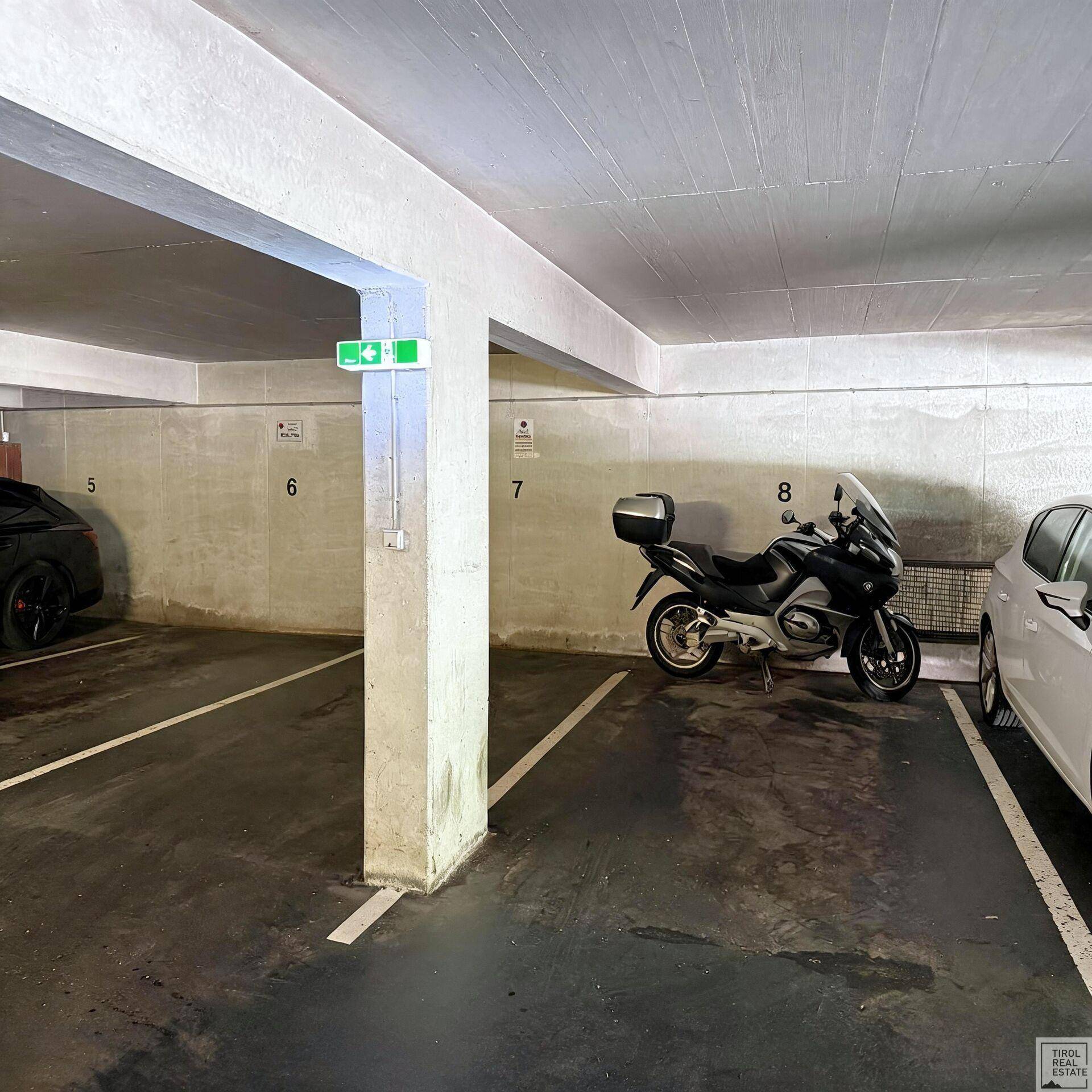 Tiefgarage mit nummerierten Stellplätzen, Fahrzeugen und Betonstützen, bietet sichere Parkmöglichkeiten.