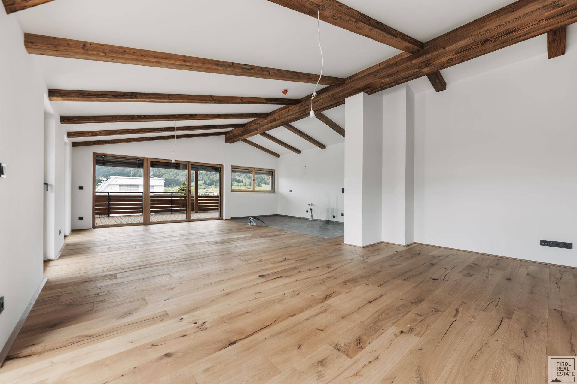 Weitläufiger, unmöblierter Raum mit Holzbalken und Parkettboden, bereit für die Gestaltung.