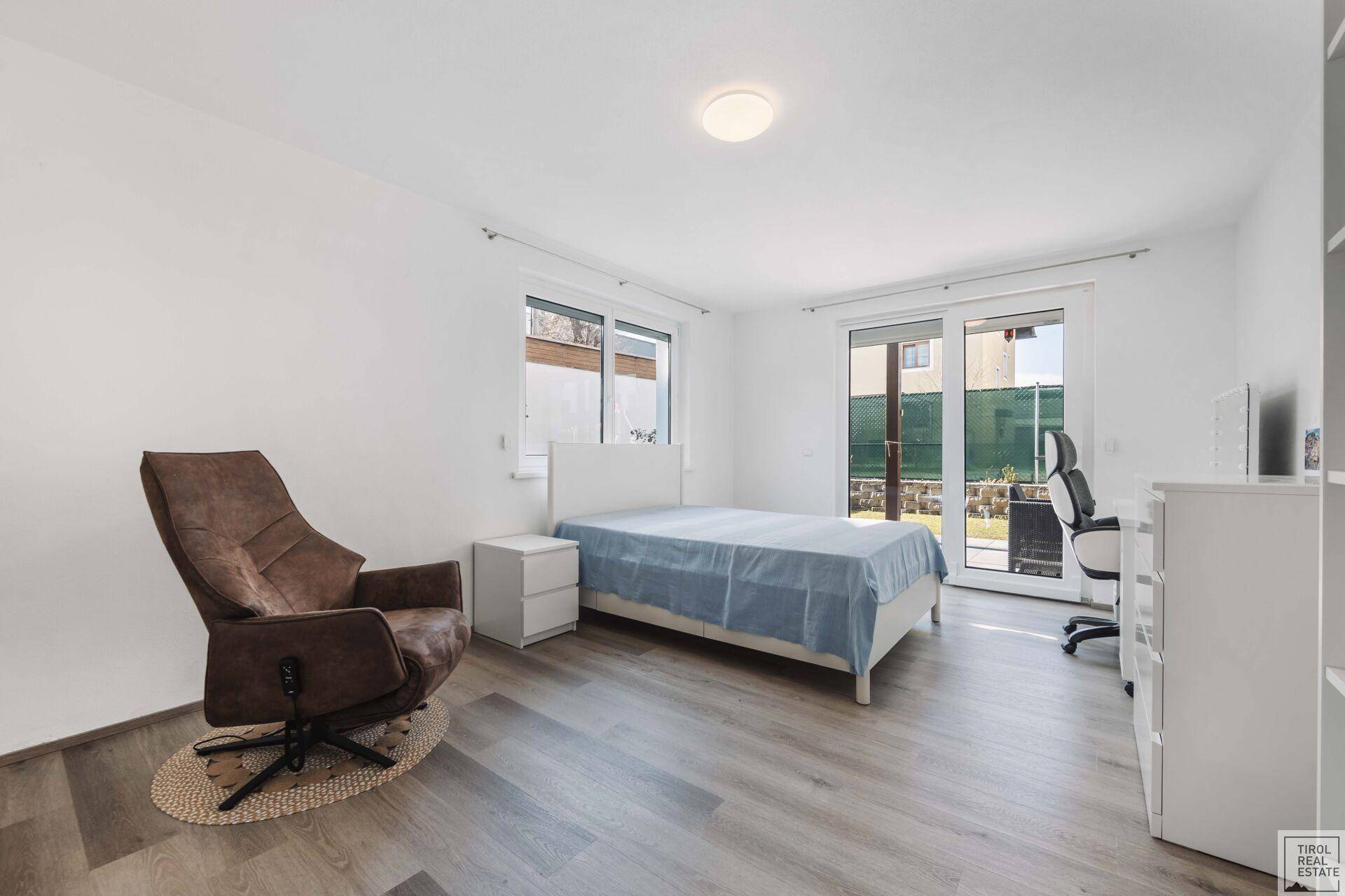 Schlafzimmer mit hellem Laminatboden, Zugang zum Garten und viel Tageslicht.