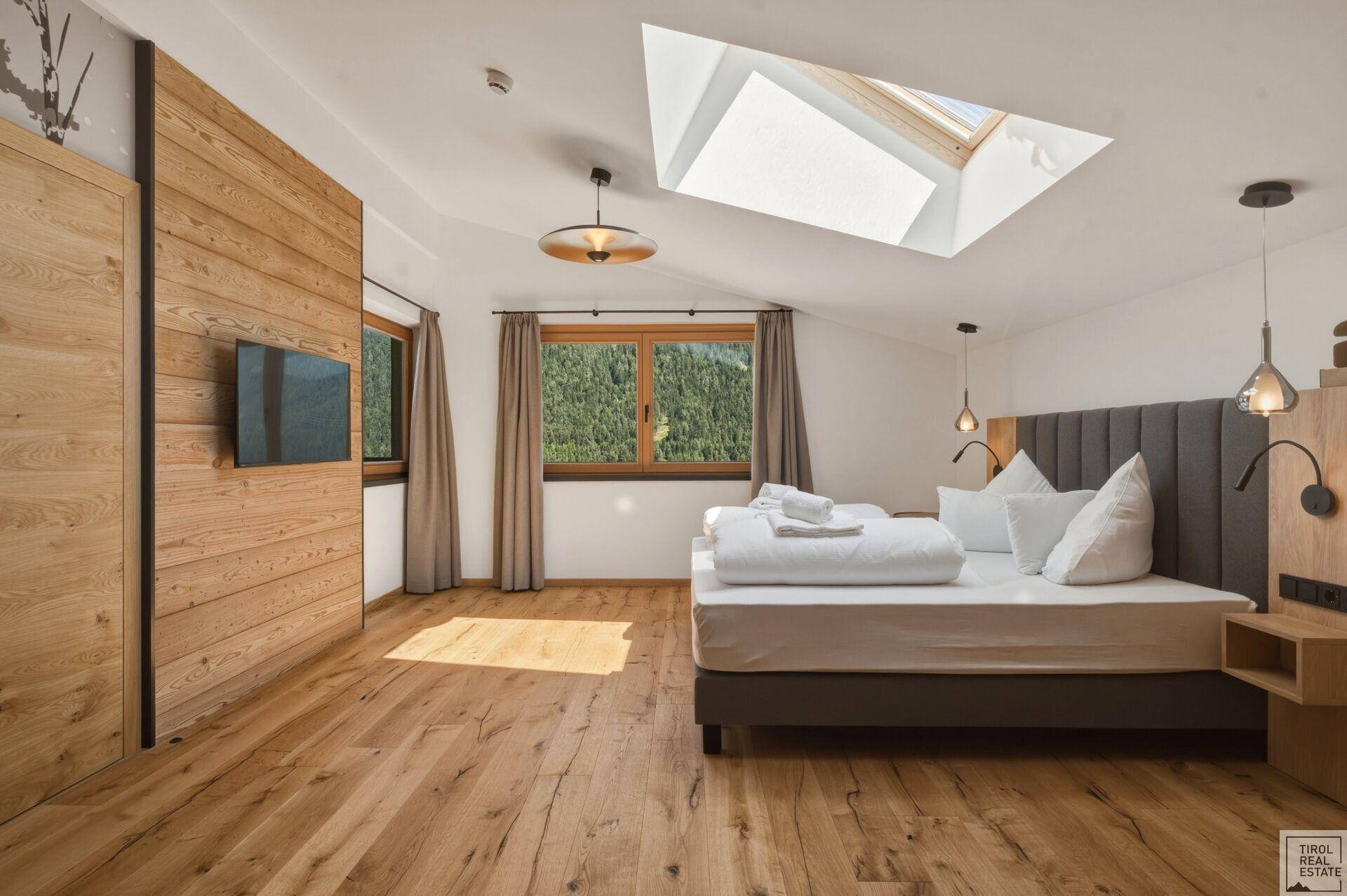 Geräumiges Schlafzimmer mit Holzboden, großem Bett und Holzwandverkleidung.