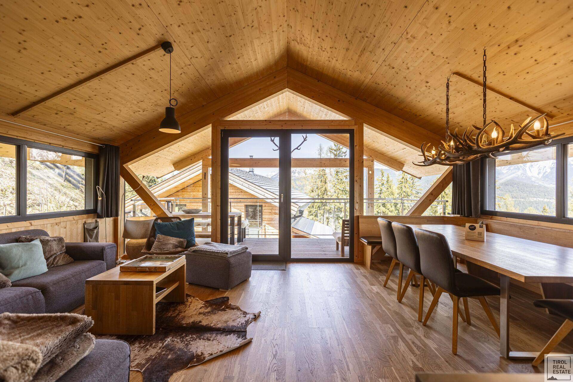 Gemütlicher Wohn-Essbereich im alpinen Stil mit Holzbalkendecke und Bergblick.