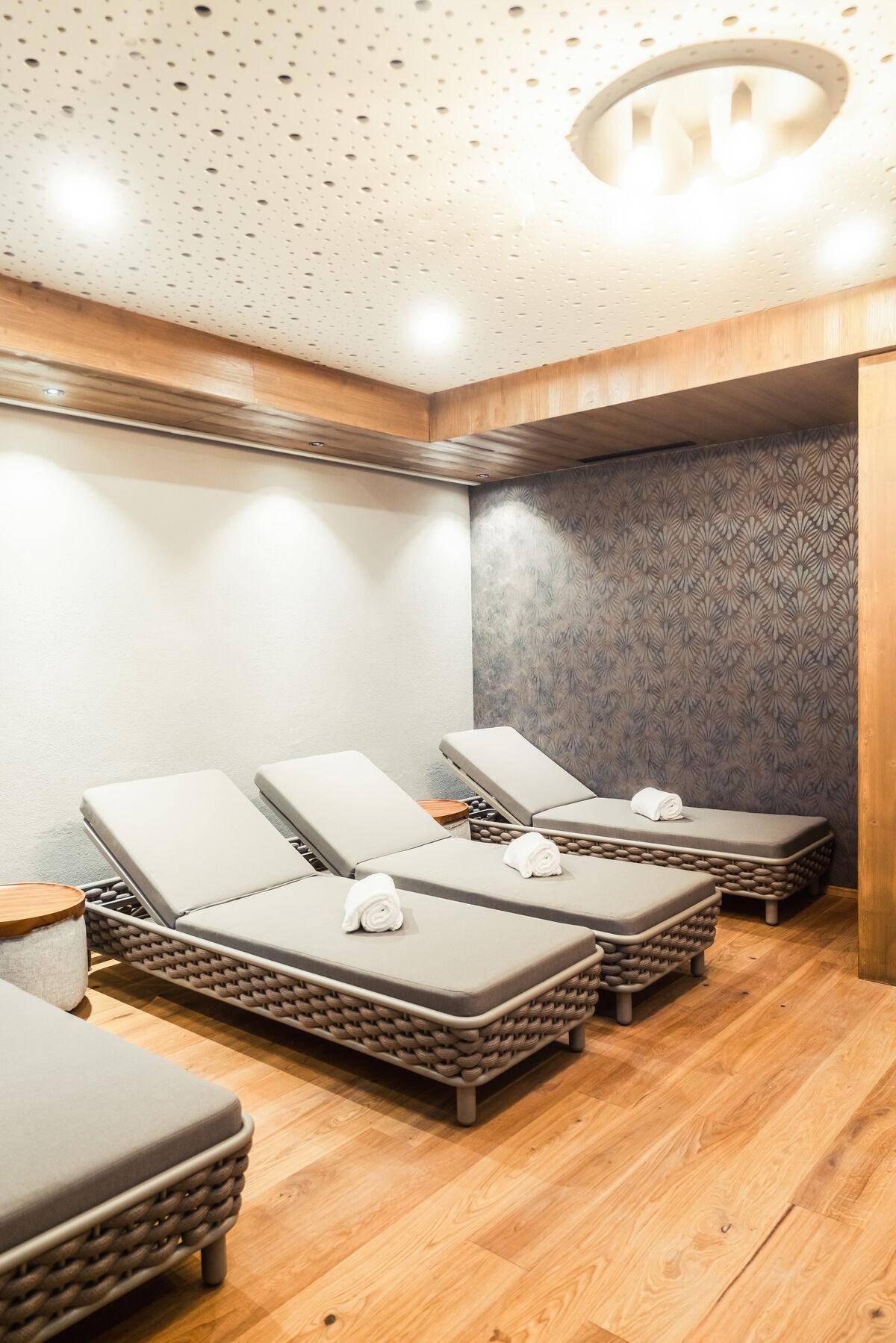 Entspannungsbereich mit bequemen Liegen, Holzboden und stimmungsvoller Beleuchtung im Wellnessbereich.