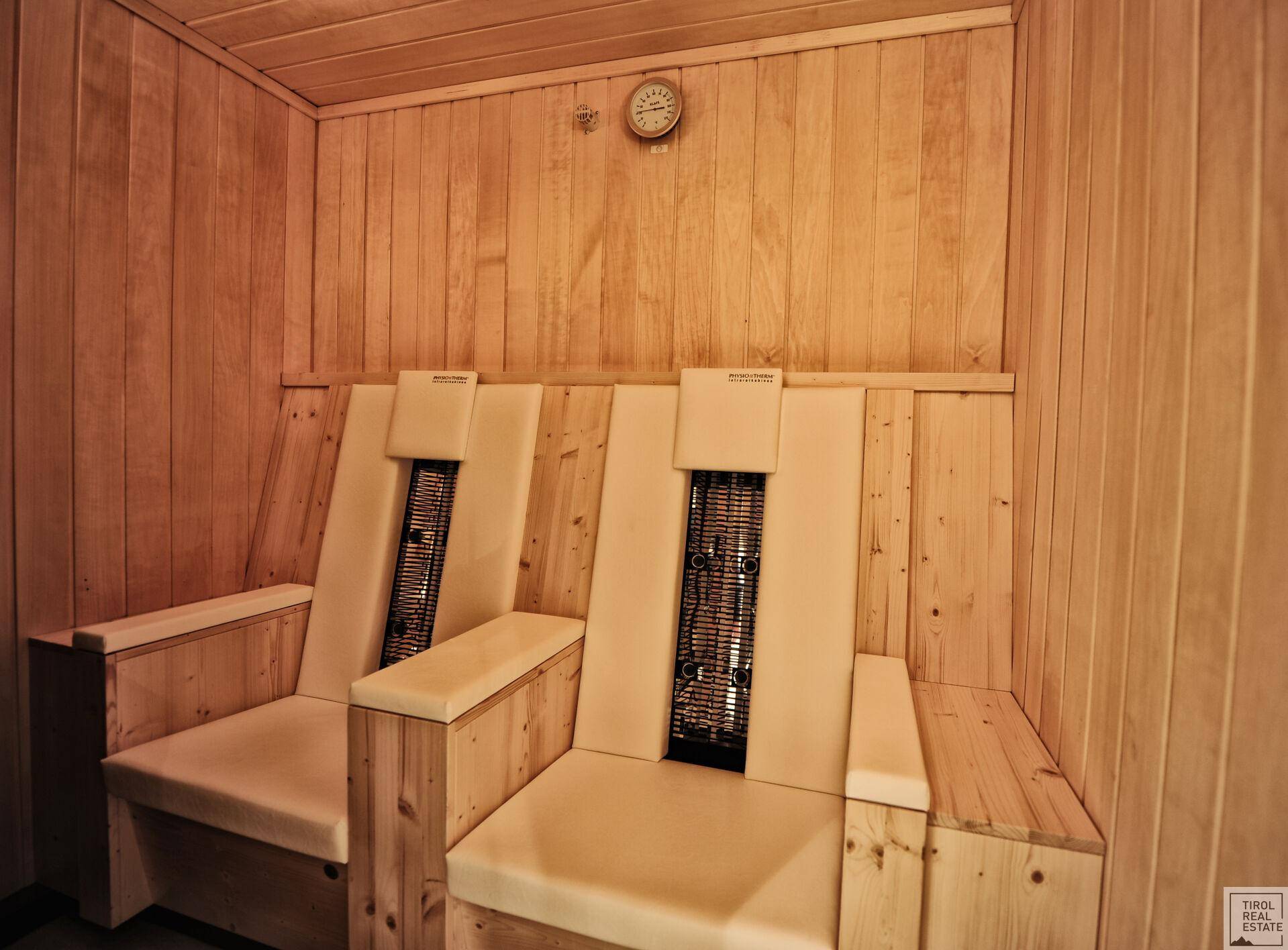 Innenansicht einer Sauna oder Infrarotkabine mit Holzbänken und einer Uhr an der Wand.