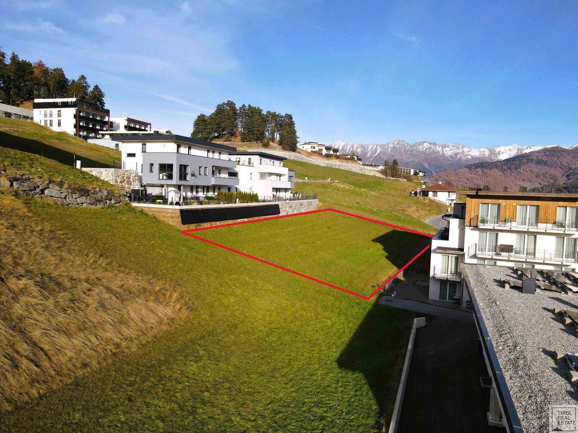 Baugrundstück in sonniger Hanglage, umgeben von zeitgenössischer Architektur und mit Fernsicht.