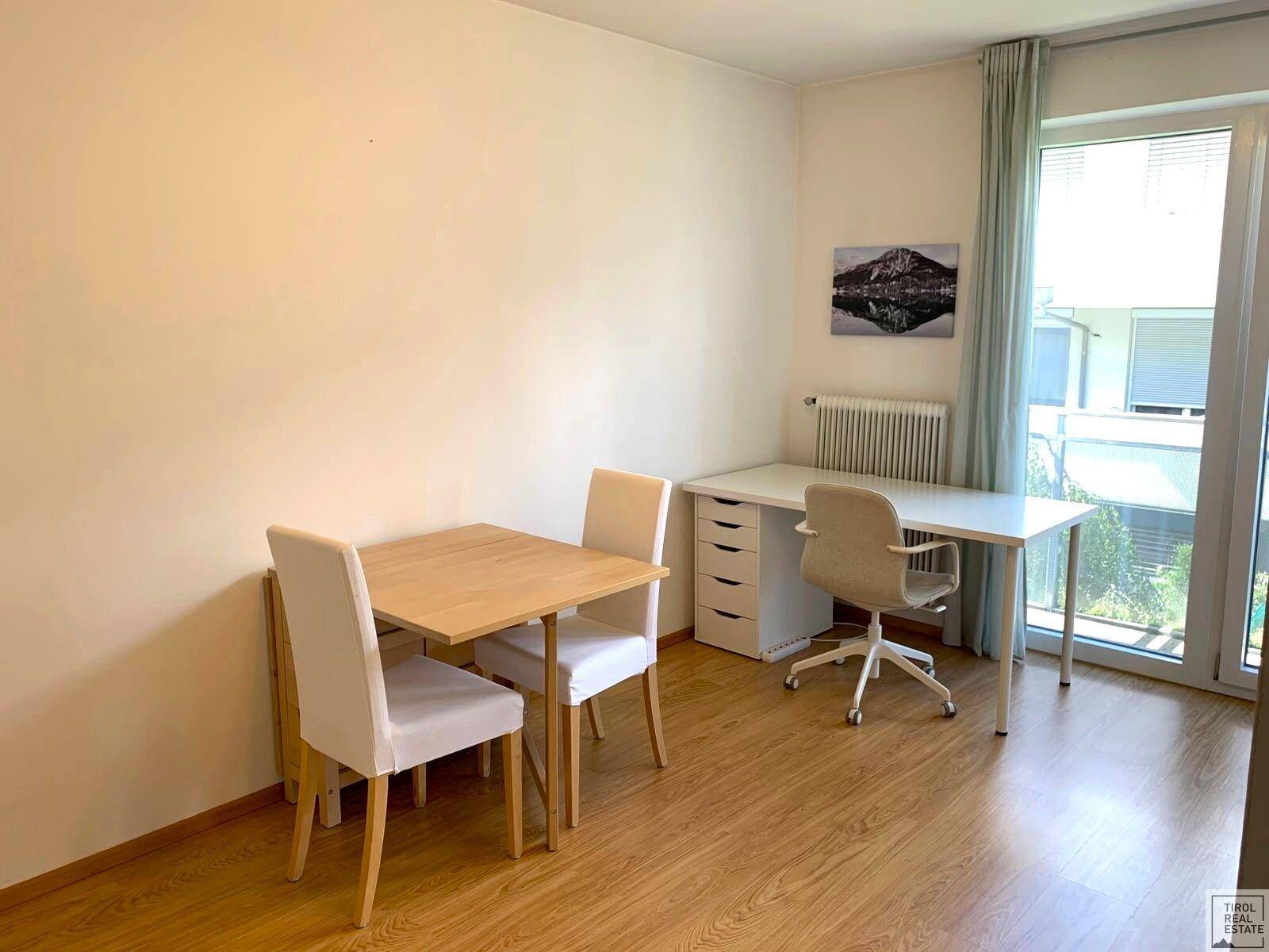Geräumiger Wohnbereich mit hellem Holzboden, Schreibtisch und Essbereich, ideal für flexibles Wohnen.