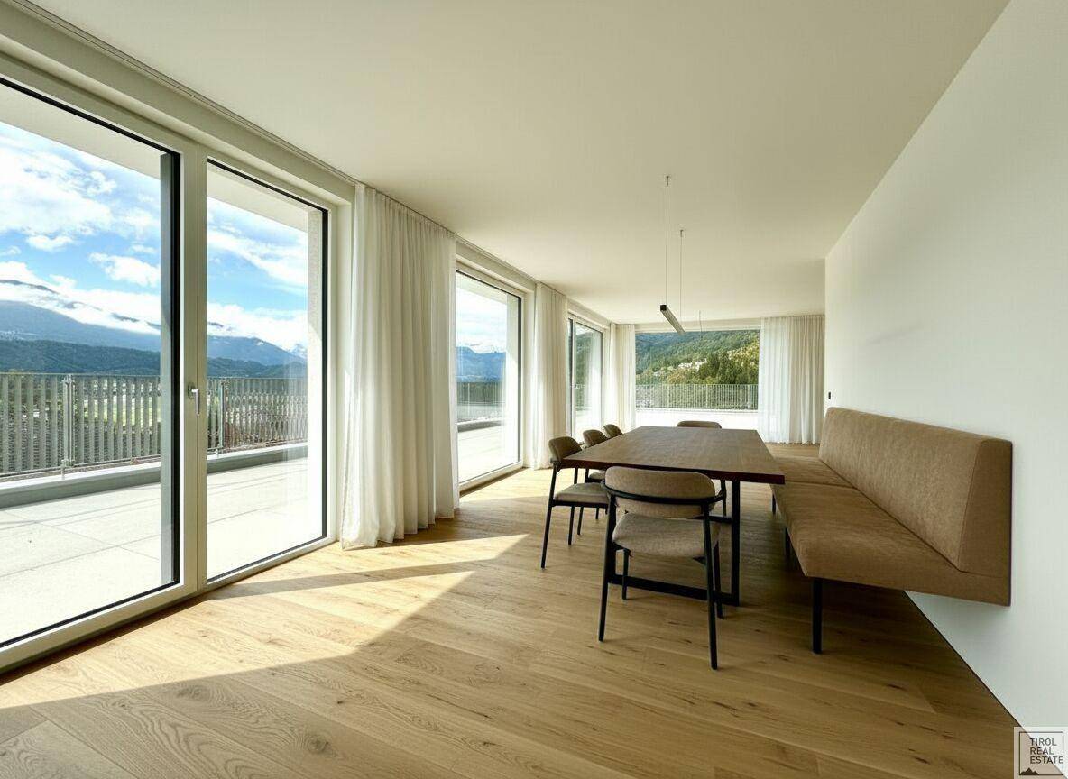 Heller Essbereich mit Holzboden, großen Fenstern und Panoramablick auf die Berge.