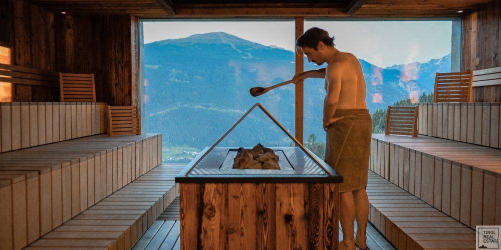 Geräumige Sauna mit Holzvertäfelung und großem Fenster mit Bergblick.