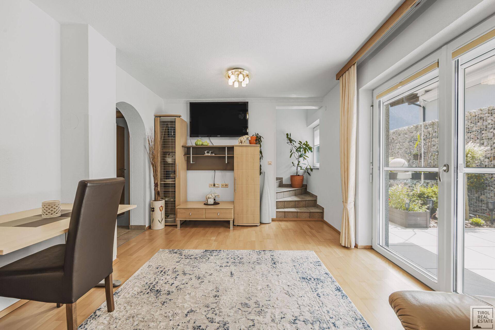 Geräumiges Wohnzimmer mit Parkettboden, TV-Bereich und Treppe zum Obergeschoss.
