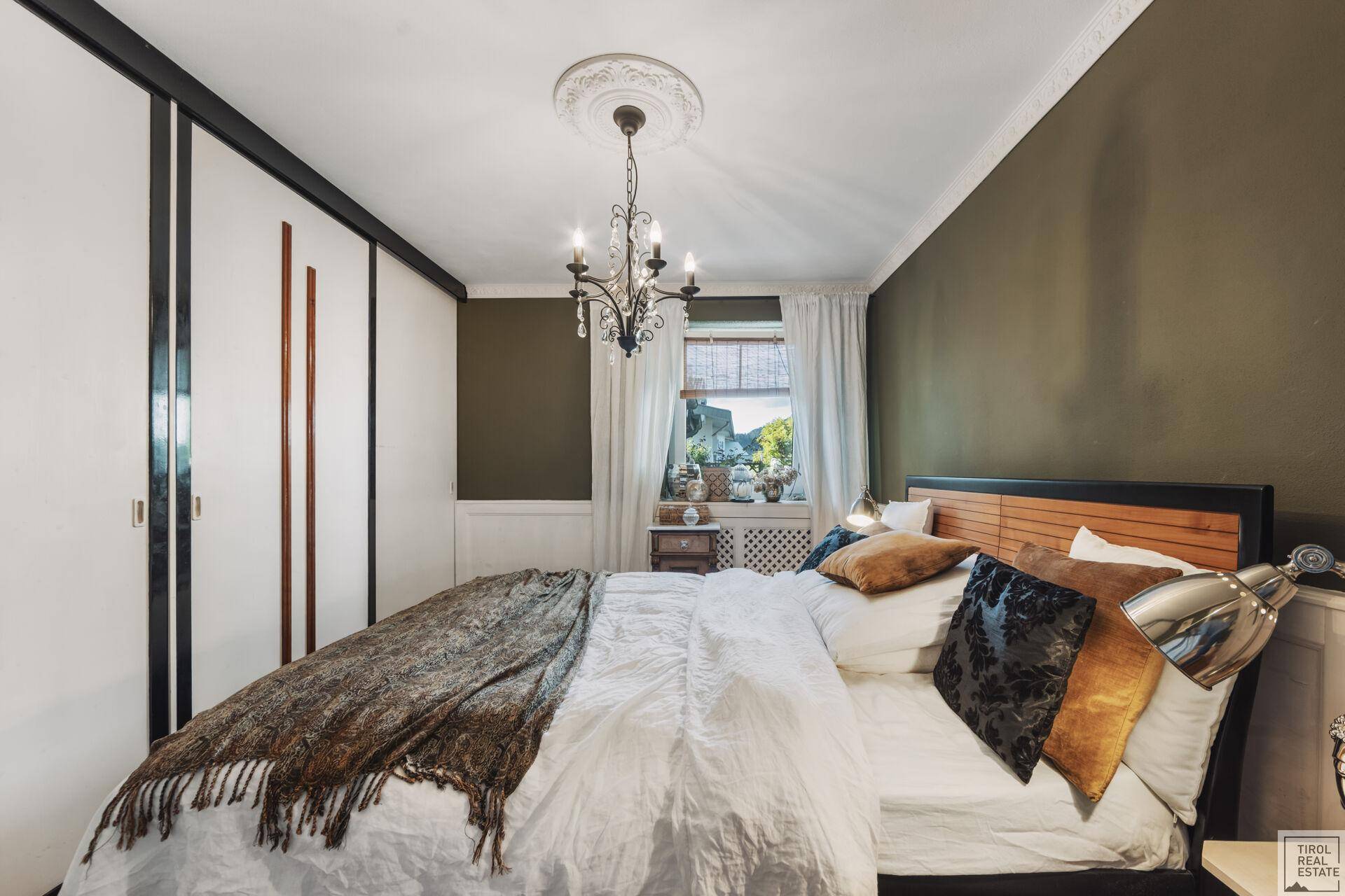 Helles Schlafzimmer mit integrierten Kleiderschränken, Holzboden und klassischer Deckenleuchte.