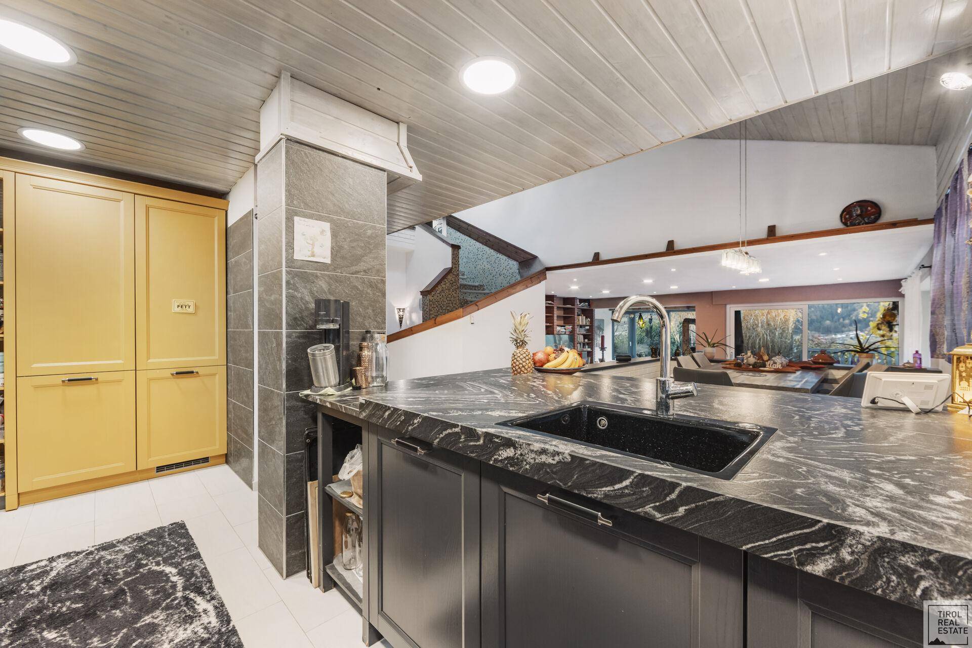 Offene Küche mit Kücheninsel, Spüle und Blick auf den angrenzenden Wohnbereich.