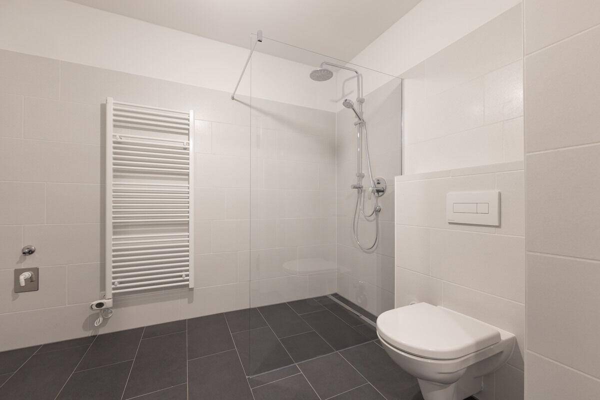 Modernes Badezimmer mit ebenerdiger Dusche, Wand-WC und beheiztem Handtuchhalter.