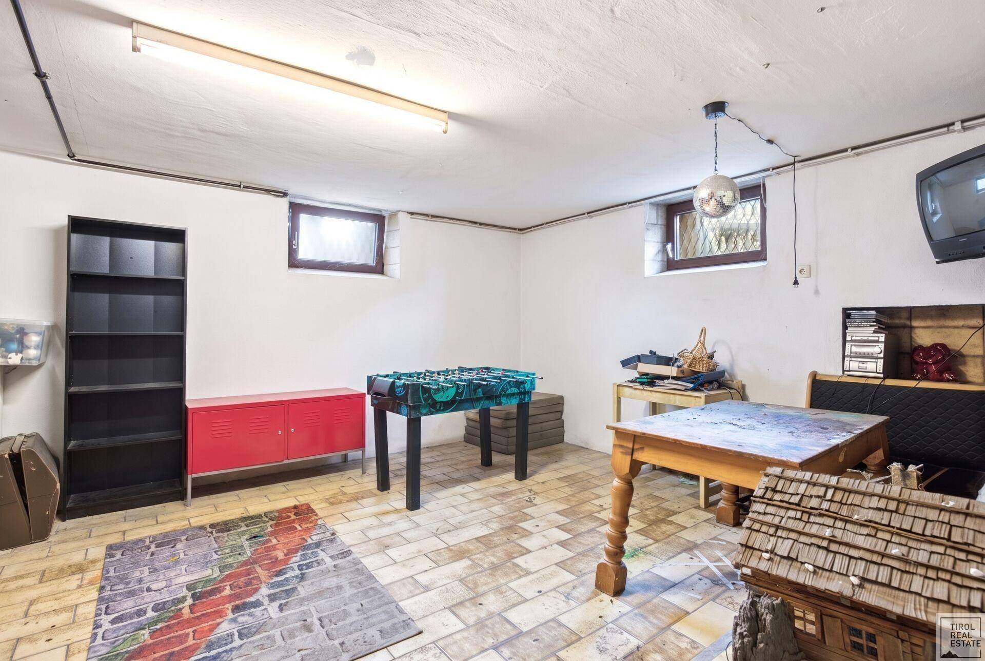 Geräumiger Kellerraum, eingerichtet als Spielzimmer mit Fliesenboden und kleinen Fenstern.