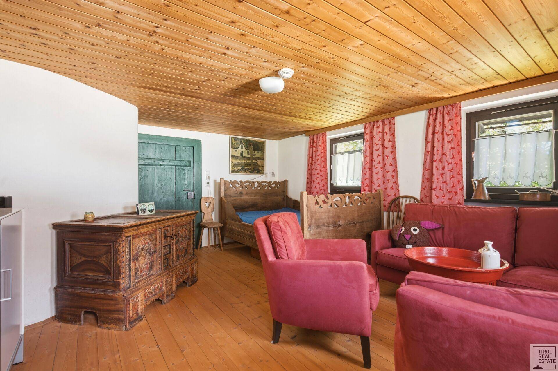 Gemütliches Wohnzimmer mit Holzdielenboden, Holzdecke und traditionellen Möbeln.