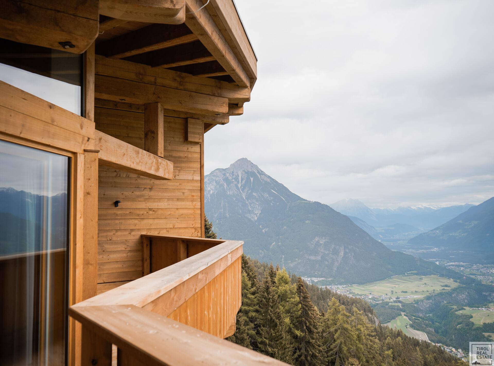 Holzbalkon mit atemberaubendem Blick auf die umliegende Berglandschaft und das Tal.