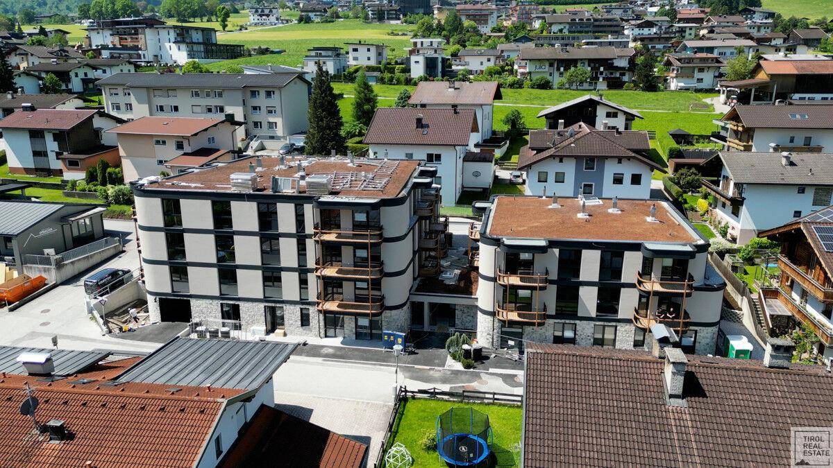 Überblick über eine moderne Wohnanlage mit Flachdächern und Balkonen in alpiner Umgebung.