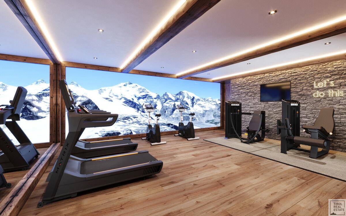 Fitnessraum mit modernen Geräten, Holzboden und beeindruckendem Panoramablick auf die Berge.